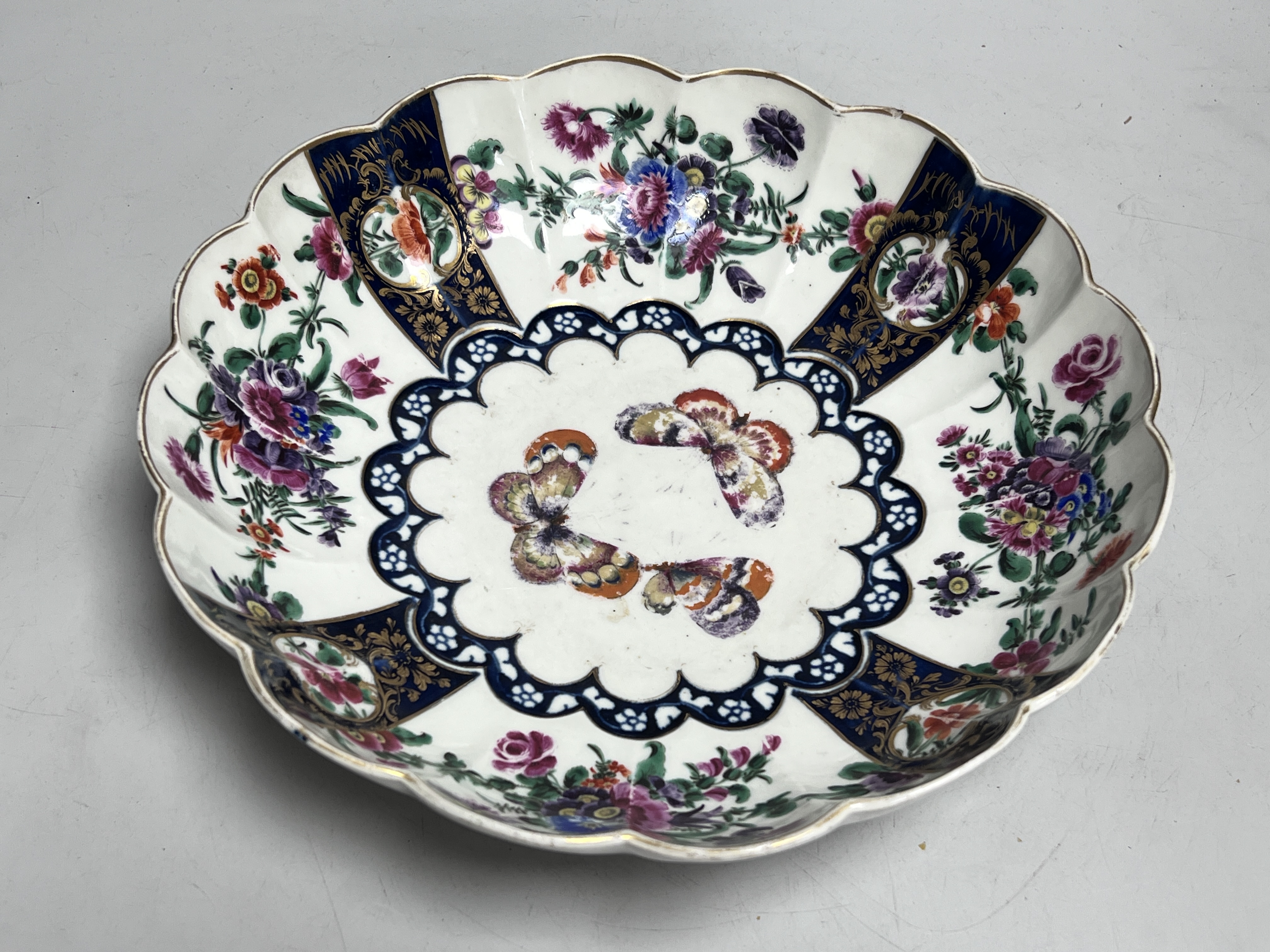 A Worcester fluted dish painted with butterflies and flowers in the manner of James Giles, seal mark, c.1770, 26cm diameter
